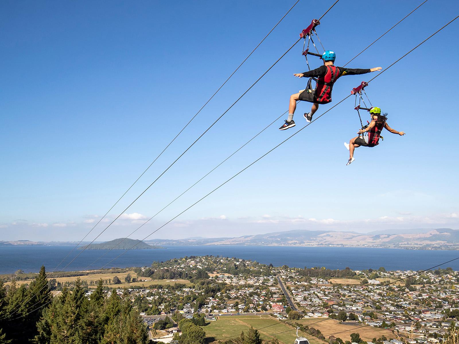 Two people high up in the air doing the zipline