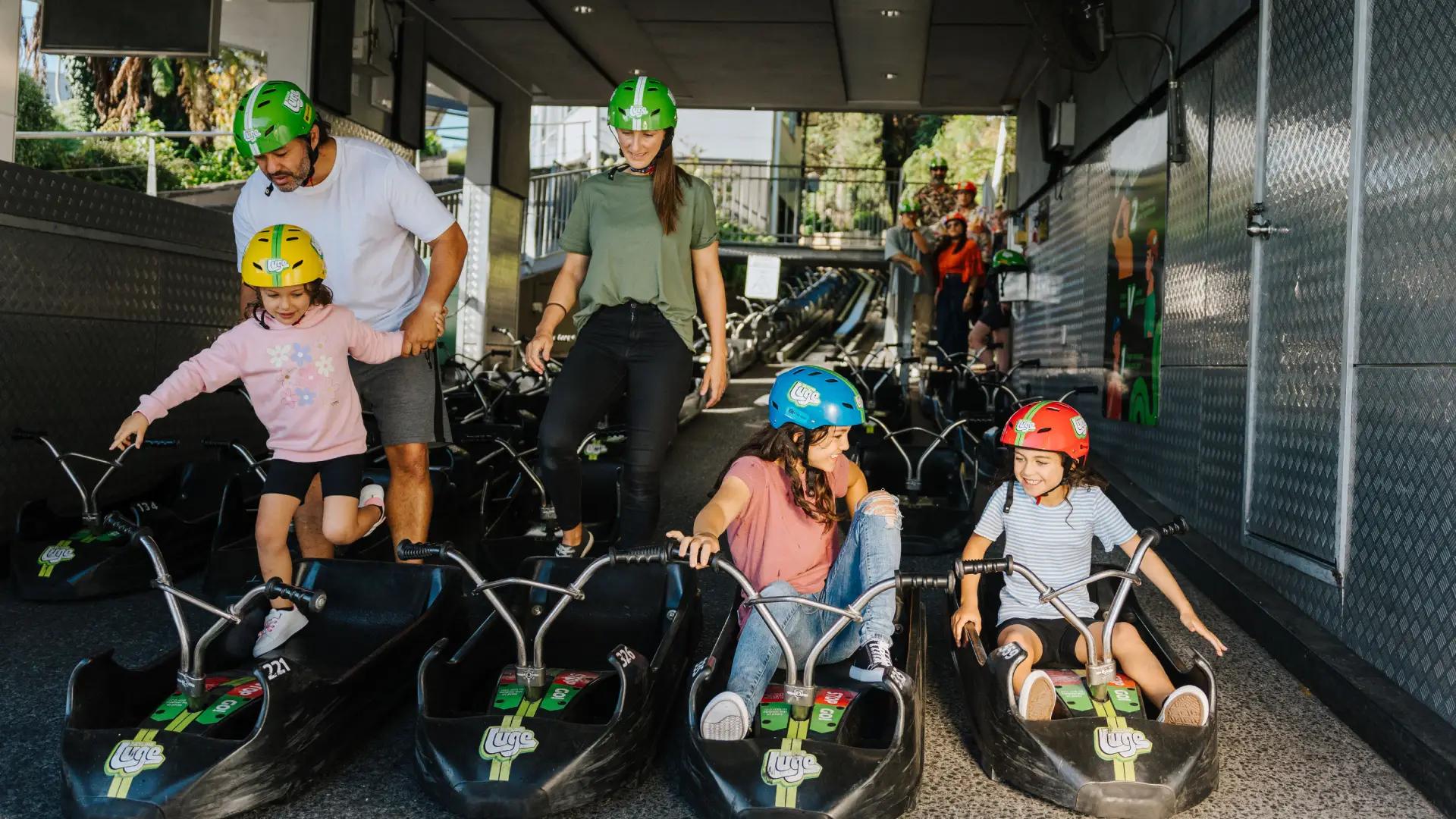 A family prepares for their Luge ride at Skyline Rotorua, helping kids into carts while others get seated and ready to go.