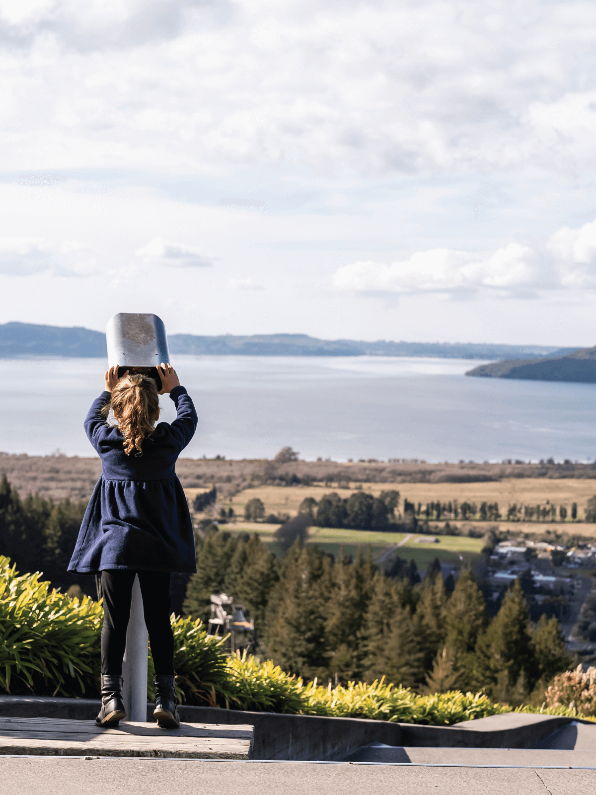 Young girl looks through a telescope at Skyline Rotorua, taking in scenic lake and forest views from Mount Ngongotaha.