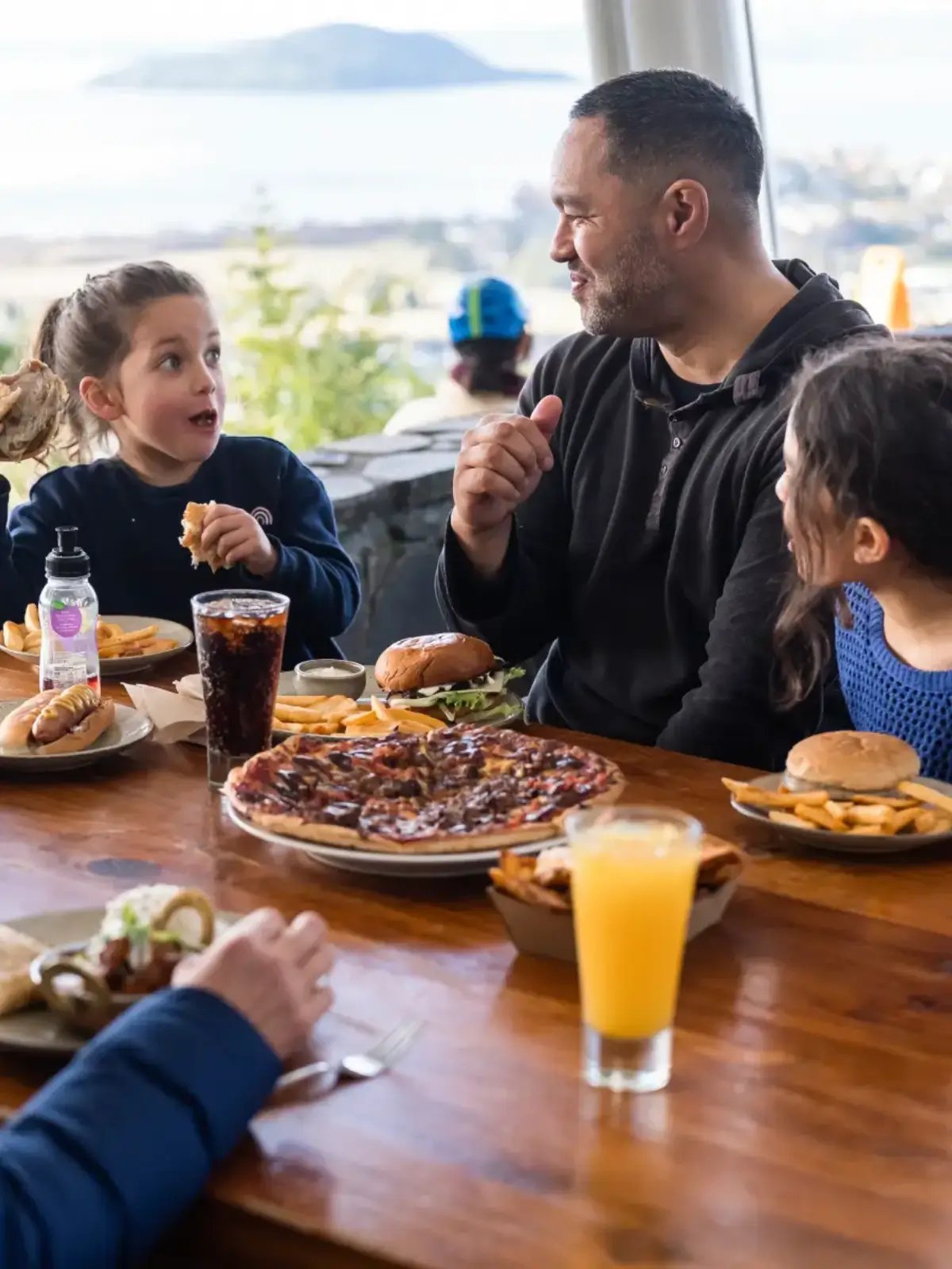 Family enjoying casual dining with burgers and drinks overlooking Rotorua from Skyline Gondola