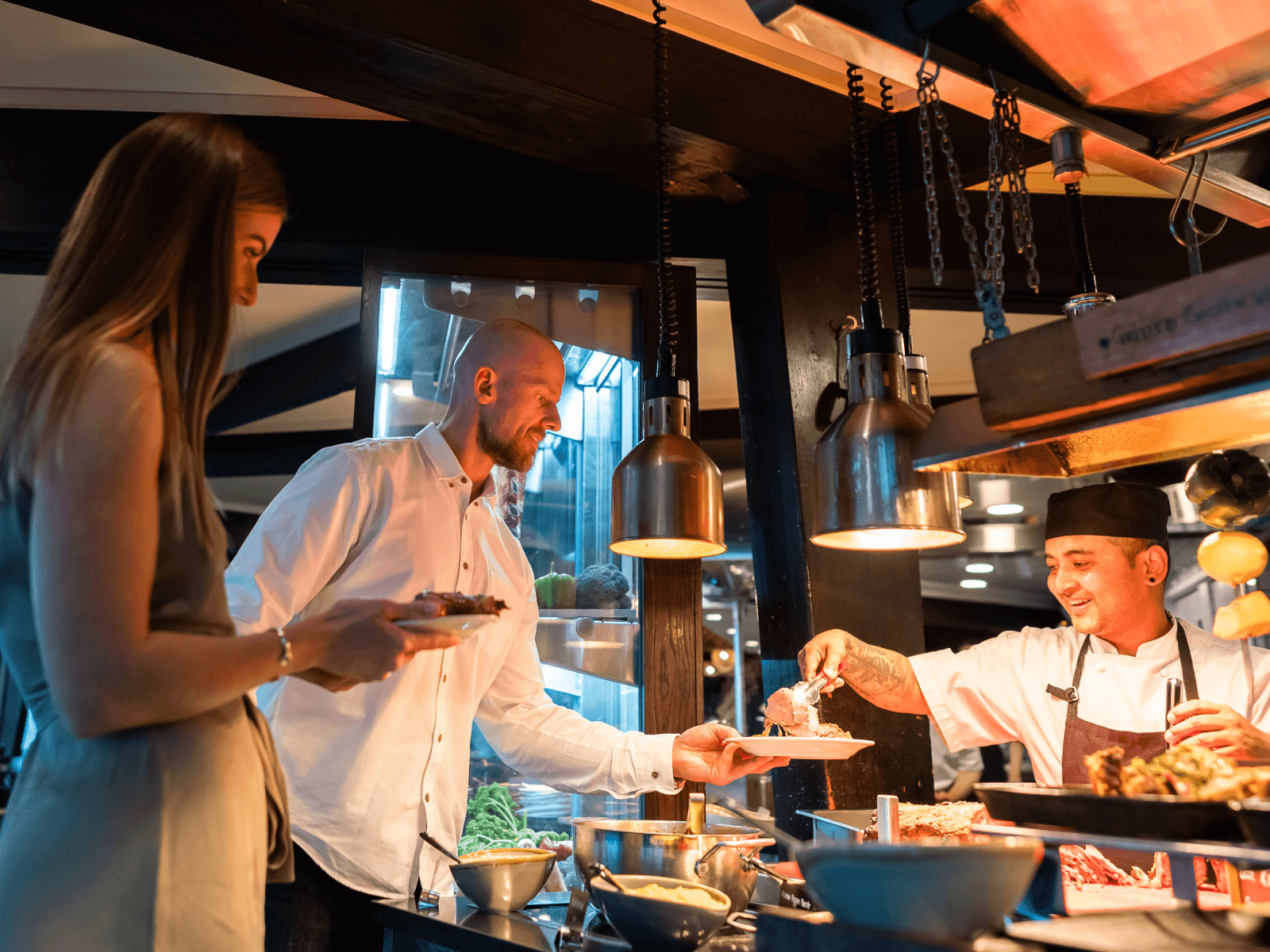 Chef serving hot food to smiling guests at Stratosfare Restaurant buffet at Skyline Rotorua.