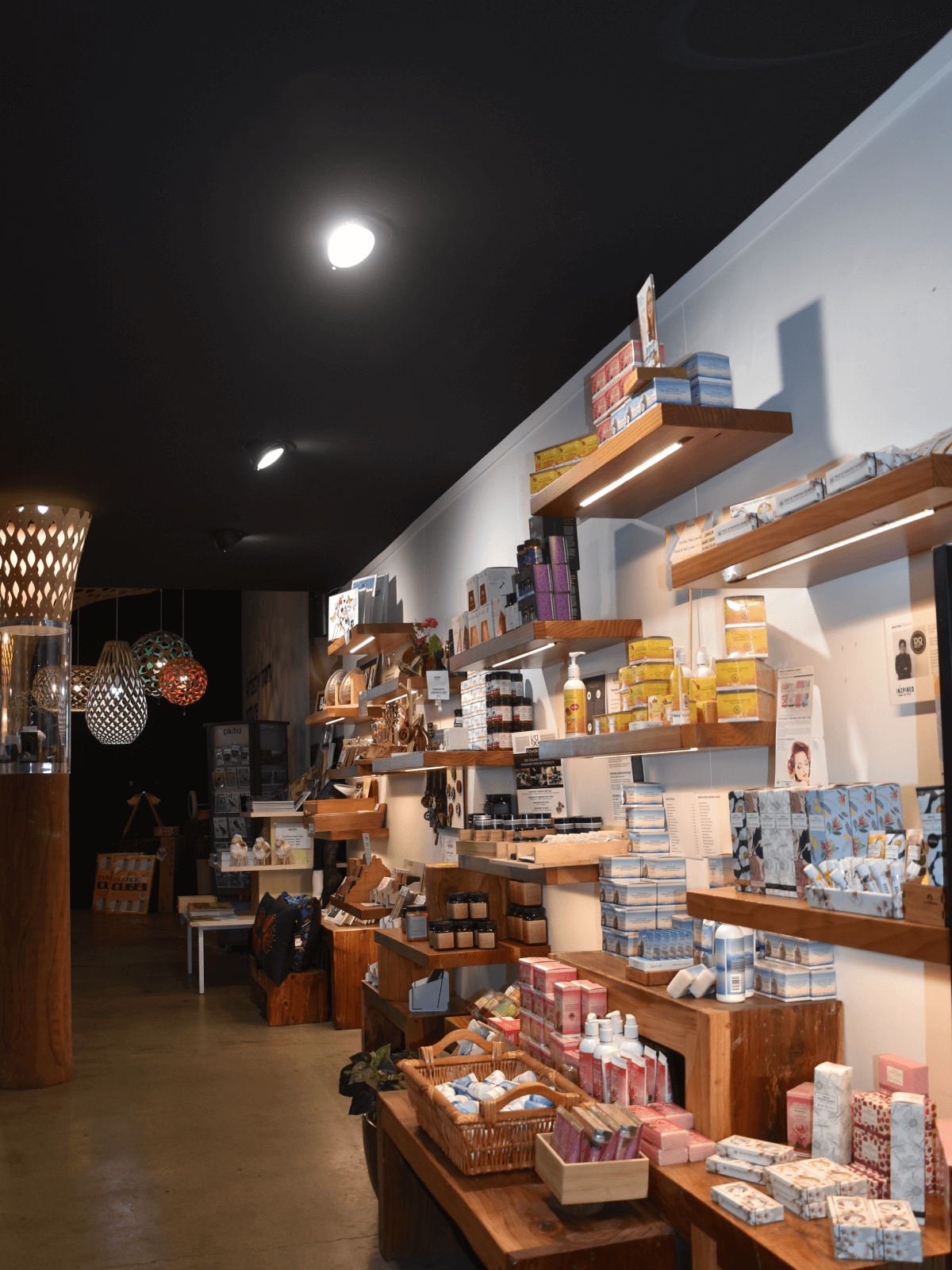 Shelves of soaps, skincare, and gifts line the wall at the Skyline Rotorua iNZpired store, with warm wooden displays and lighting.