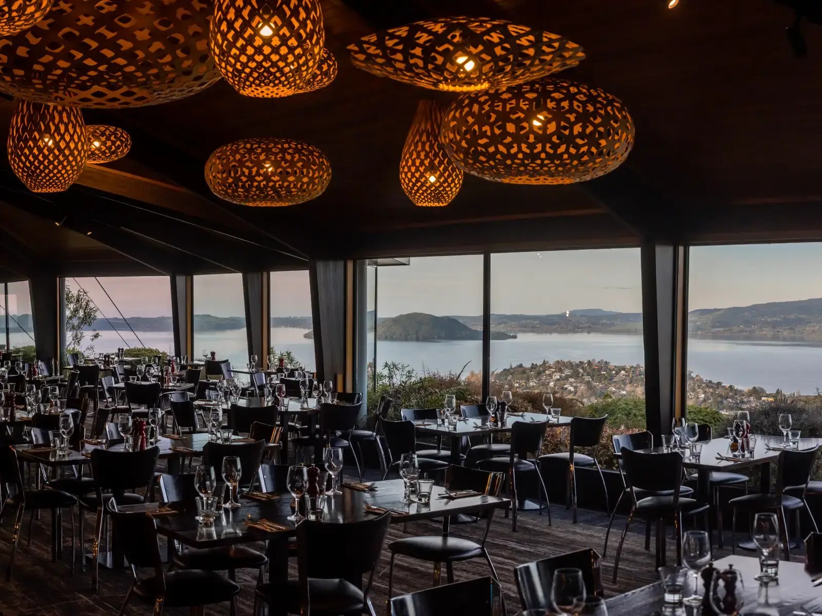 Stratosfare Restaurant at Skyline Rotorua set for dining, with floor to ceiling windows overlooking Lake Rotorua.