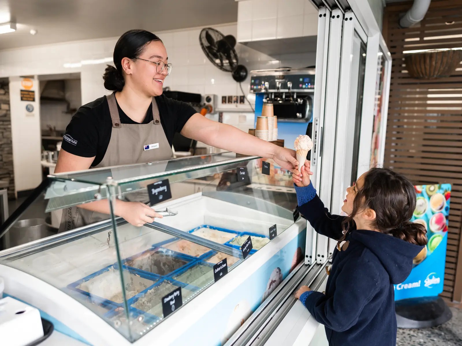Staff member handing an ice cream cone to a smiling child at Skyline Rotorua.