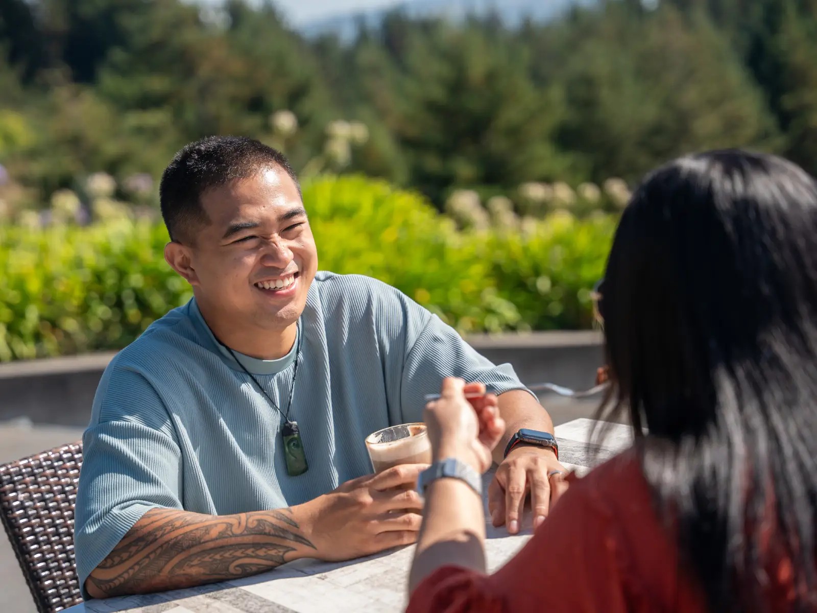 Friends enjoying drinks together at Market Kitchen Café at Skyline Rotorua on a sunny day.
