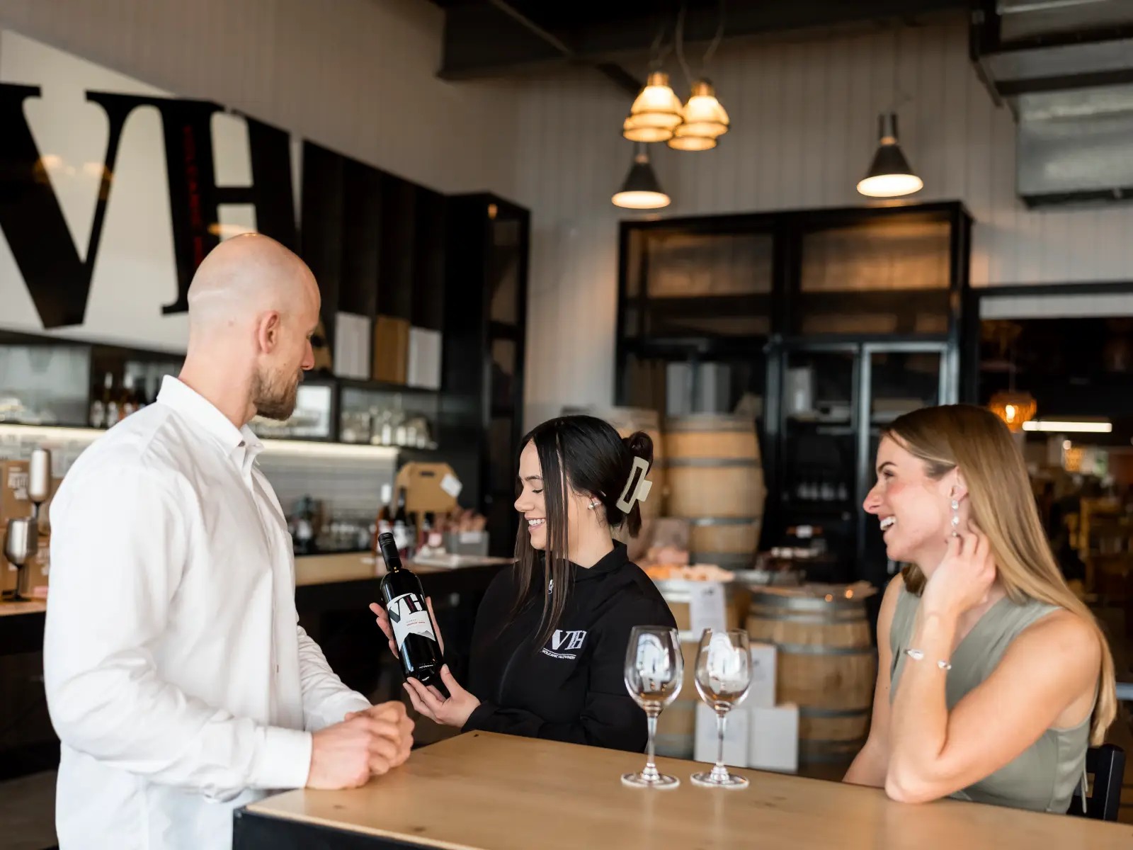 A Volcanic Hills staff member shares a bottle of wine with two guests during a relaxed wine tasting session.