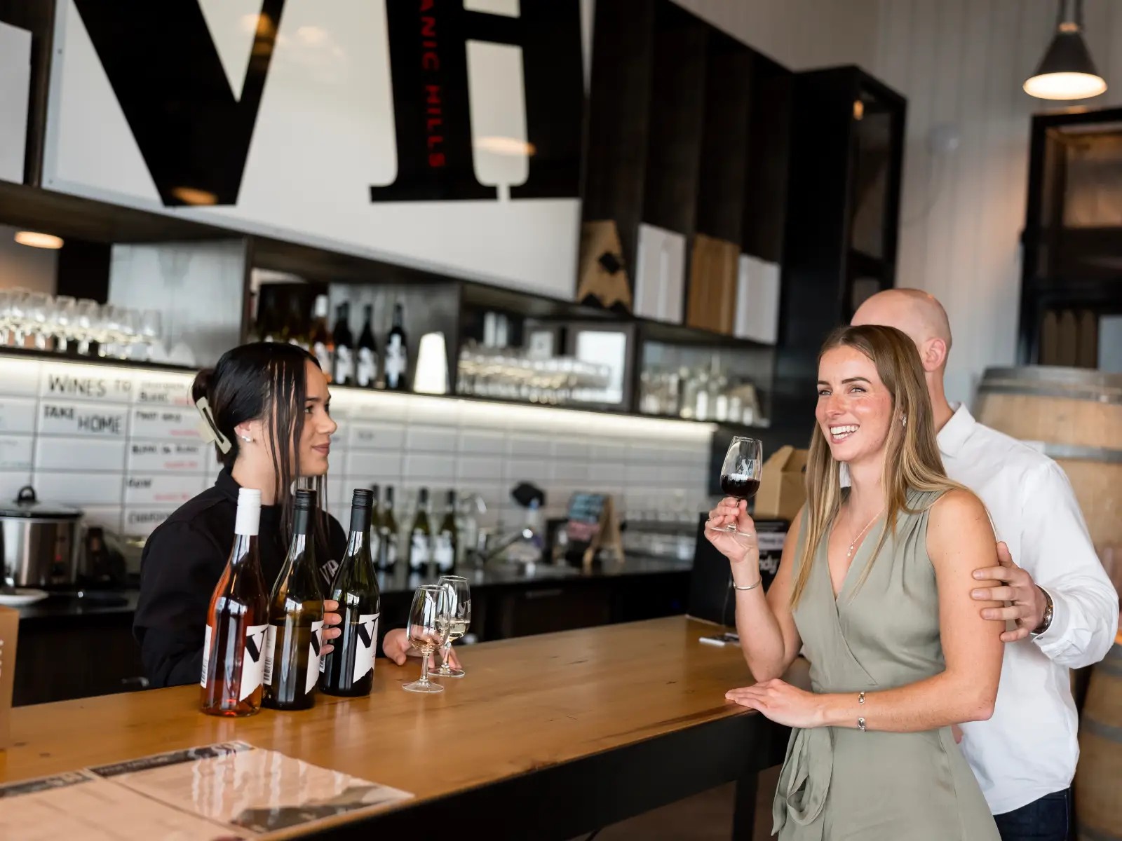 A couple enjoys a wine tasting at Volcanic Hills as a staff member presents a selection of local wines.