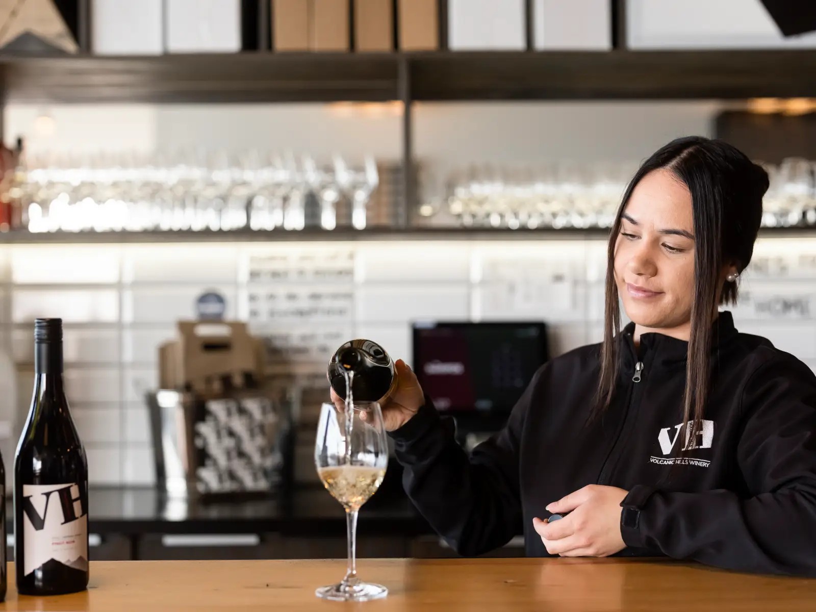 A Volcanic Hills staff member pours white wine into a glass at the Volcanic Hills Tasting Roomm.