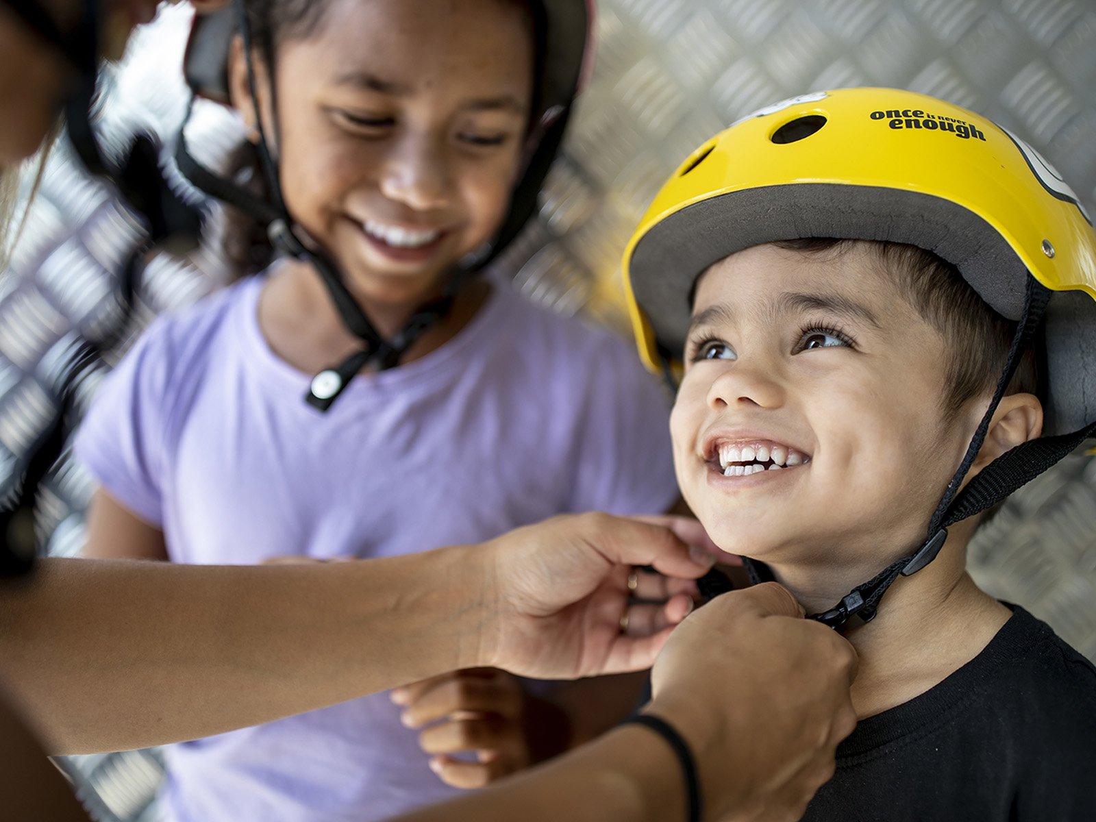 Two young kids getting their helmets on
