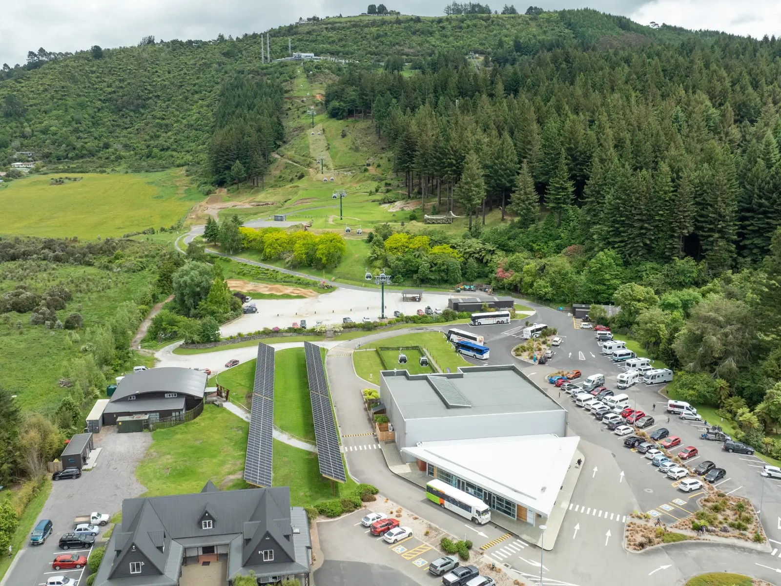 Aerial view of Skyline Rotorua’s solar panel installation and gondola base surrounded by lush forest and hillside.